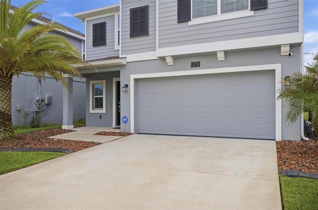 A two-story gray house features a two-car garage, a palm tree, and a concrete driveway — 1251 SAND TRAP COURT, DAYTONA BEACH, FL