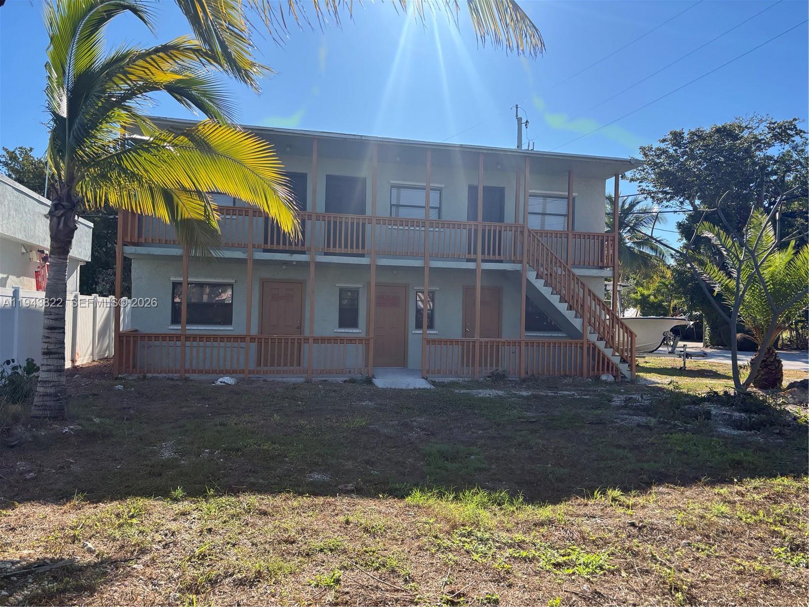 A two-story apartment building features wooden balconies, exterior staircases, and palm trees in the yard — 103365 Overseas Hwy # C, Key Largo FL 33037, KEY LARGO, FL