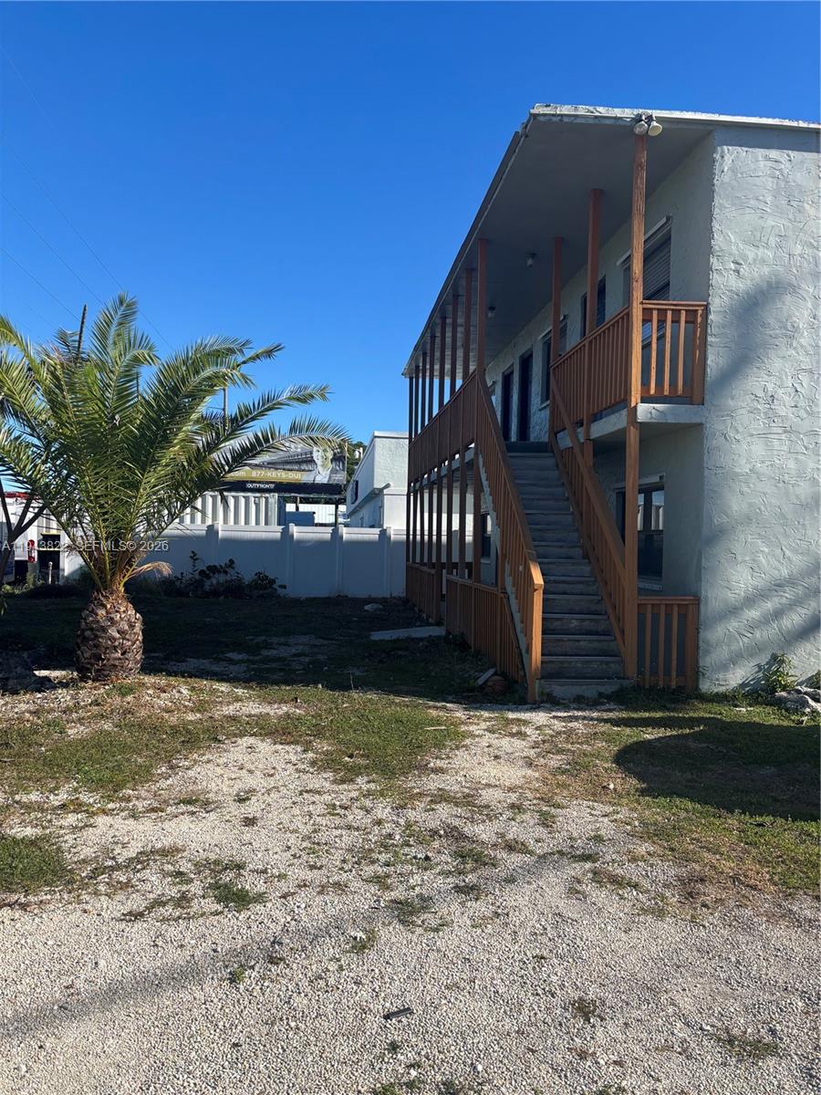 A two-story building with an exterior wooden staircase and balcony stands beside a palm tree — 103365 Overseas Hwy # C, Key Largo FL 33037, KEY LARGO, FL