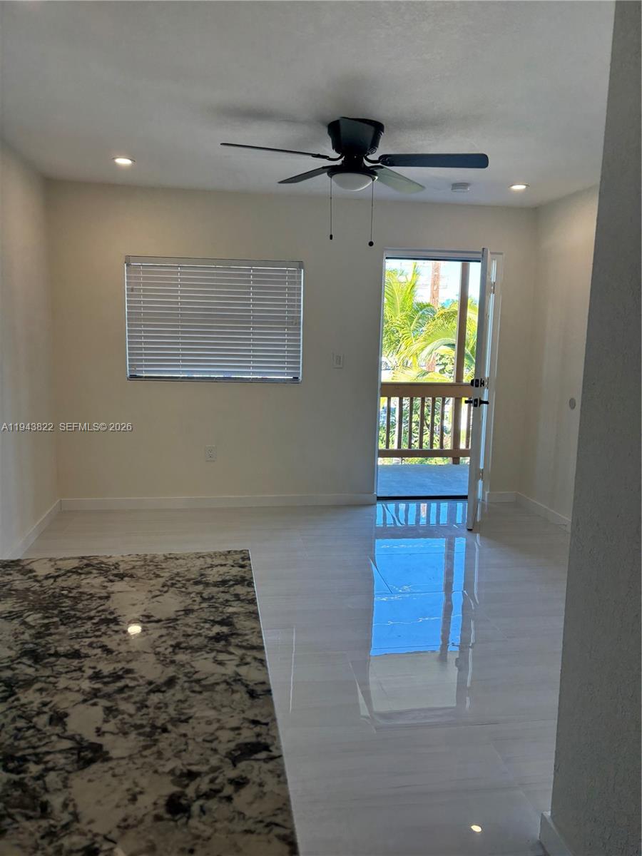 A room with white tile floors, a ceiling fan, and a door leading to a balcony — 103365 Overseas Hwy # C, Key Largo FL 33037, KEY LARGO, FL
