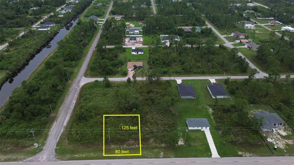 An aerial view shows a vacant rectangular lot outlined in yellow next to a paved road — 464 COLUMBUS BLVD, LEHIGH ACRES, FL