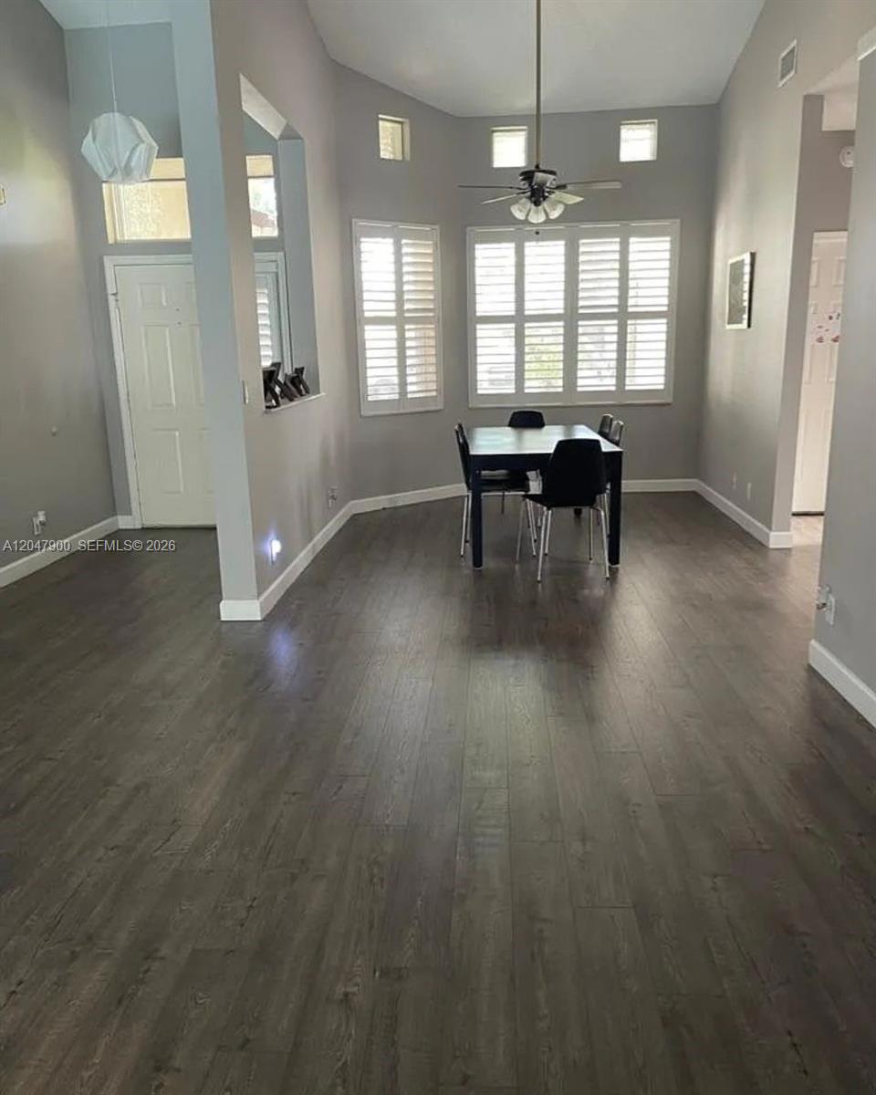A dining area with dark wood flooring, grey walls, and a black table with chairs — 10644 Edinburgh St, Cooper City FL 33026, COOPER CITY, FL