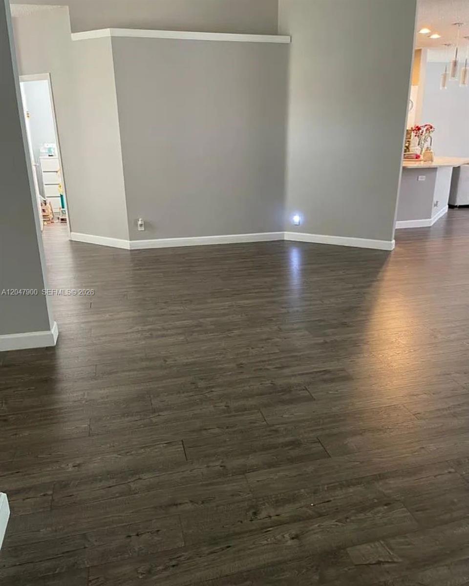 An interior view shows a room with gray walls, dark wood-look flooring, and white trim — 10644 Edinburgh St, Cooper City FL 33026, COOPER CITY, FL