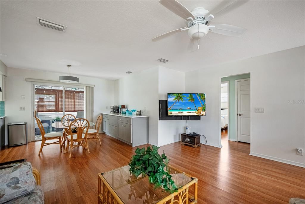 A living and dining area features hardwood floors, a ceiling fan, and a wall-mounted television — 3380 NW 44TH COURT, OCALA, FL