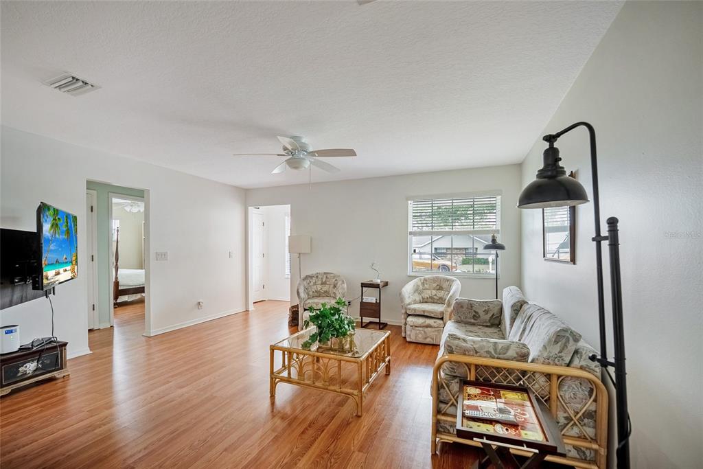A living room features wood-look flooring, a ceiling fan, a sofa, and two armchairs — 3380 NW 44TH COURT, OCALA, FL