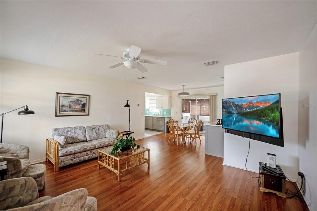 A living room with wood flooring, a floral sofa, and a wall-mounted television — 3380 NW 44TH COURT, OCALA, FL