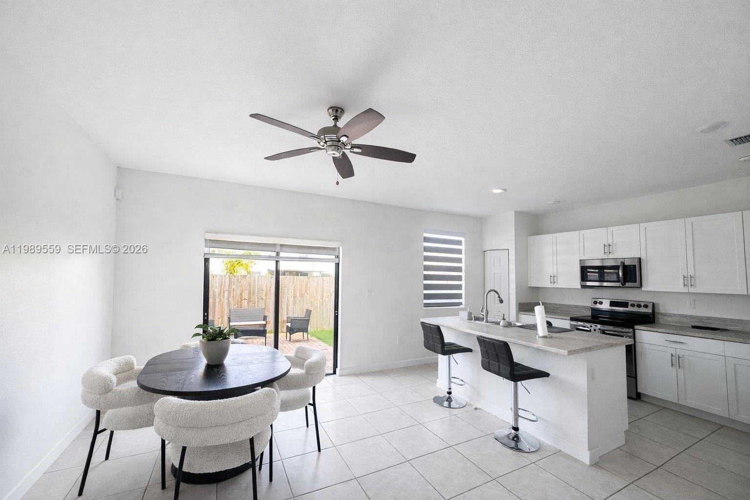 A kitchen and dining area feature white cabinetry, a breakfast bar, and a sliding door — 12767 SW 230th Ter, Miami FL 33170, MIAMI, FL
