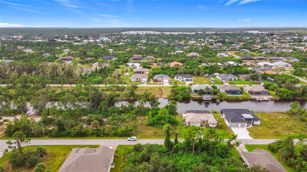 An aerial view shows houses along a canal in a suburban residential neighborhood — 15149 AMSTERDAM AVENUE, PORT CHARLOTTE, FL
