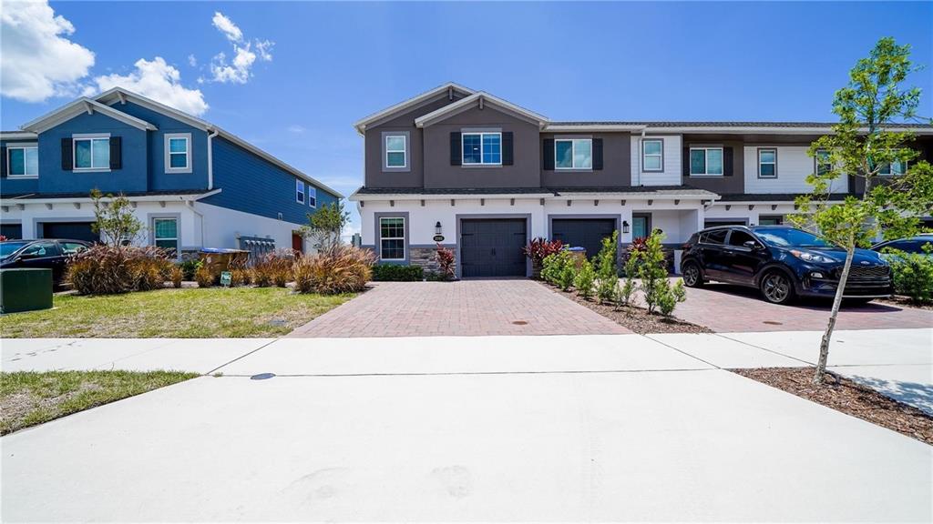 A multi-unit residential building with a brick driveway and a parked car in front — 2782 NARCOOSSEE COMMONS WAY, ST CLOUD, FL