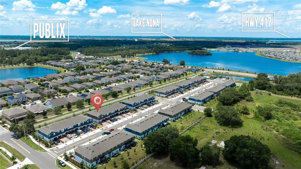 An aerial view shows a residential neighborhood of townhomes with a lake in the background — 2782 NARCOOSSEE COMMONS WAY, ST CLOUD, FL
