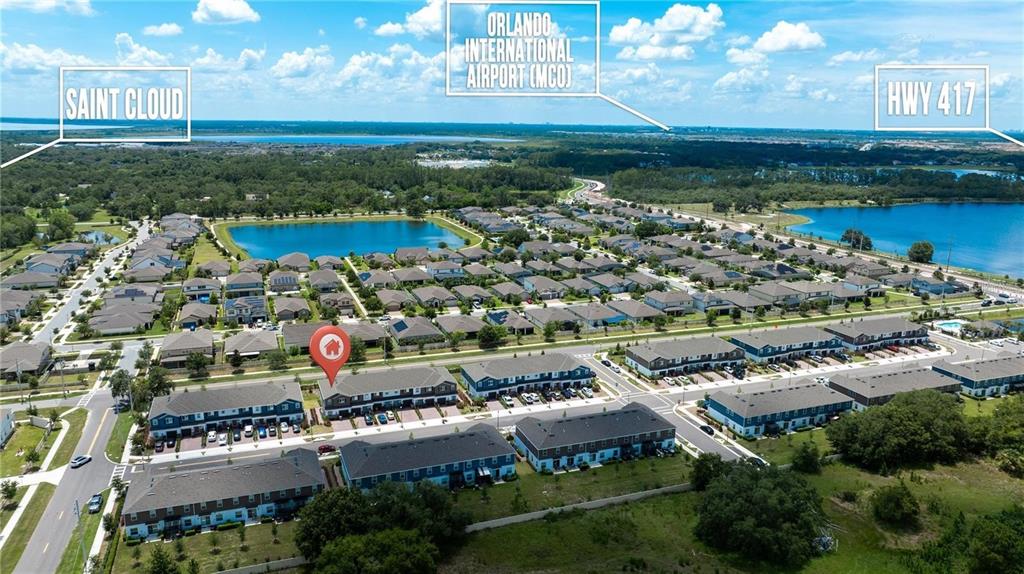 An aerial view shows a residential neighborhood with townhomes, lakes, and surrounding green space — 2782 NARCOOSSEE COMMONS WAY, ST CLOUD, FL