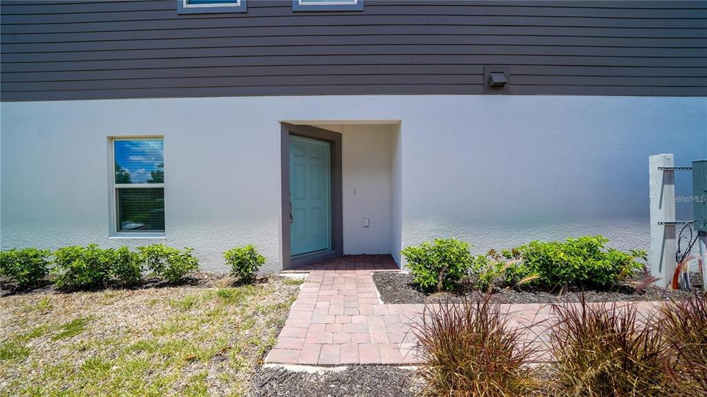 A light blue front door is set in a white stucco wall with a walkway — 2782 NARCOOSSEE COMMONS WAY, ST CLOUD, FL