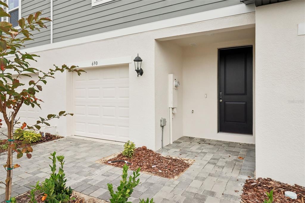 A residential exterior features a white stucco facade, a black front door, and a garage — 690 MUHLY WAY, LADY LAKE, FL