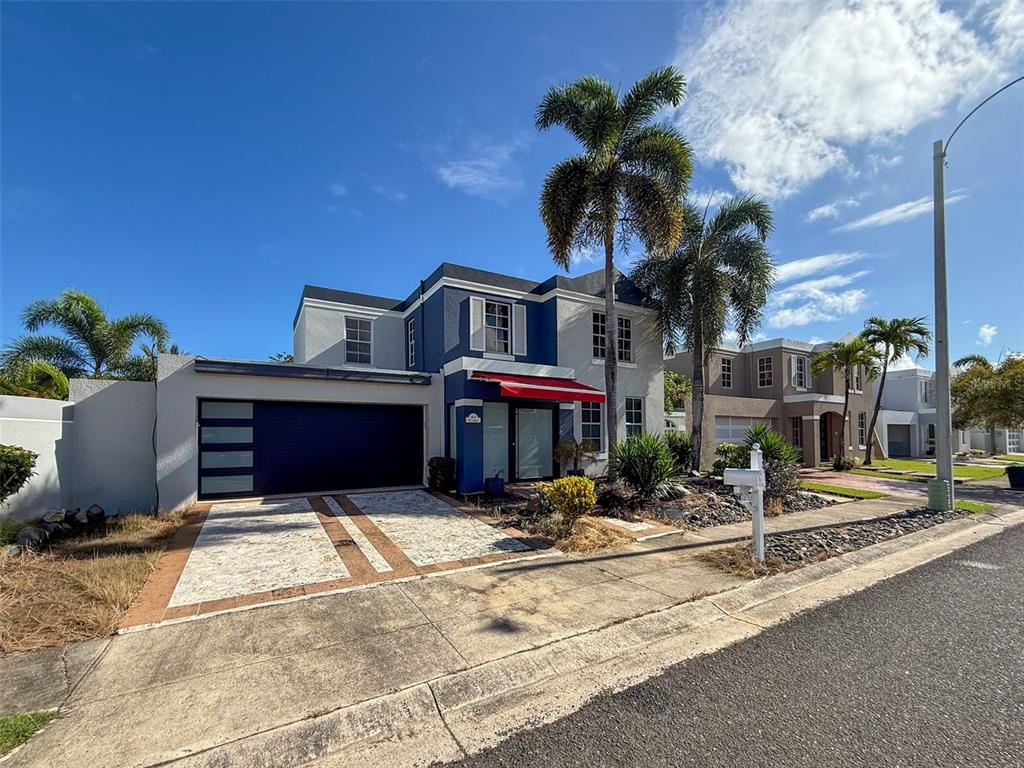 A two-story house with a blue facade, red awning, and attached garage under palm trees — 14 VIA CANGREJOS, TOA BAJA, PR