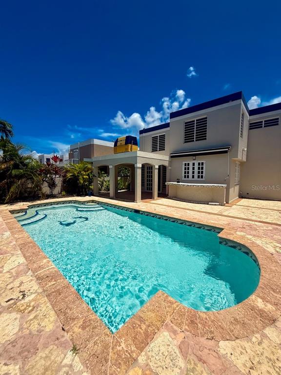A swimming pool sits in front of a two-story house with a covered patio — 14 VIA CANGREJOS, TOA BAJA, PR