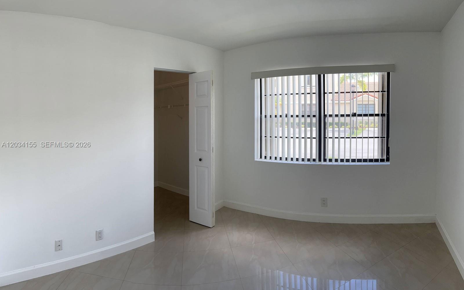 An empty bedroom features white walls, tile flooring, a closet, and a window with blinds — 6361 NW 170th Ln, Hialeah FL 33015, HIALEAH, FL