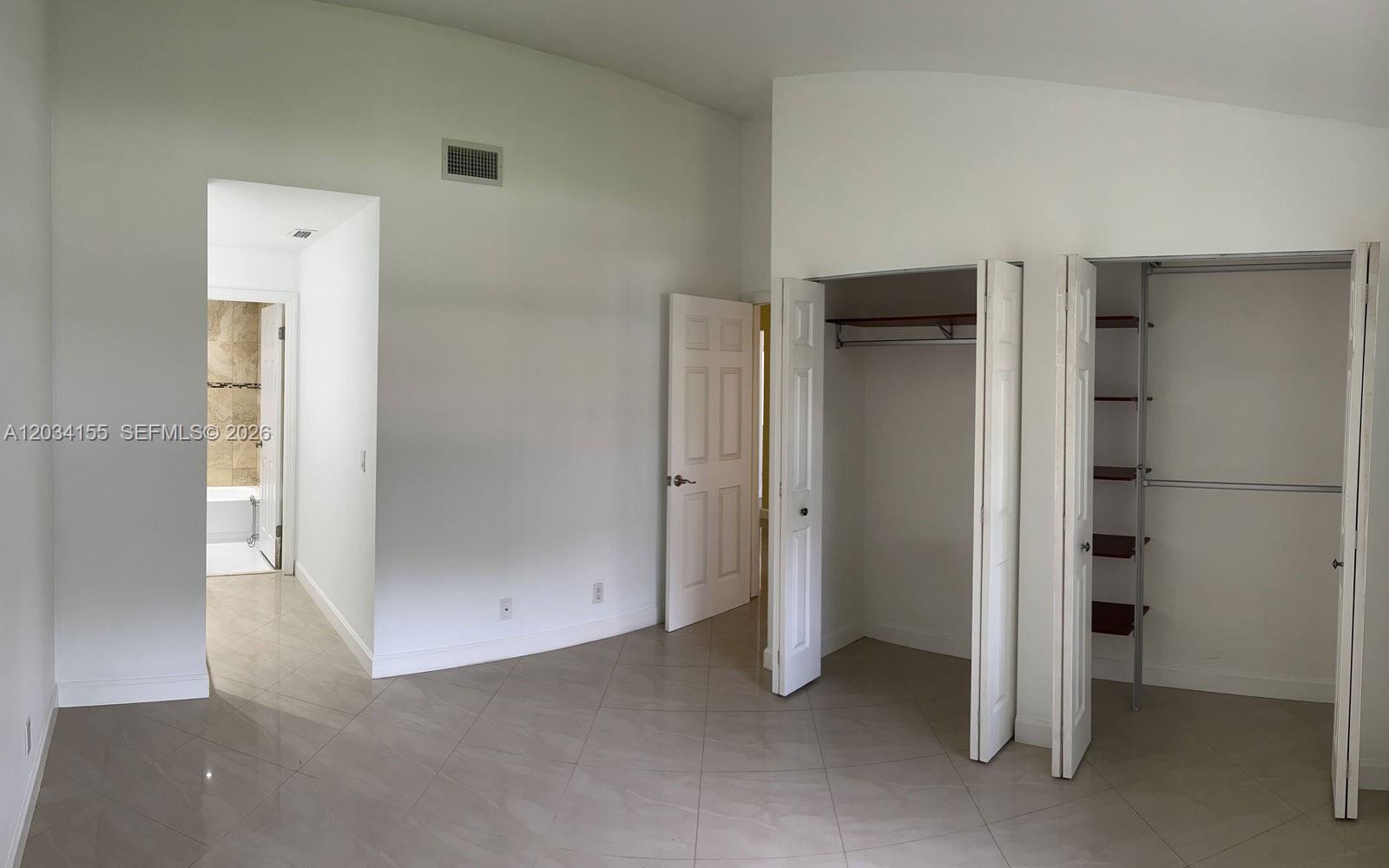 A room with light tile flooring, white walls, two open closets, and an adjacent bathroom — 6361 NW 170th Ln, Hialeah FL 33015, HIALEAH, FL