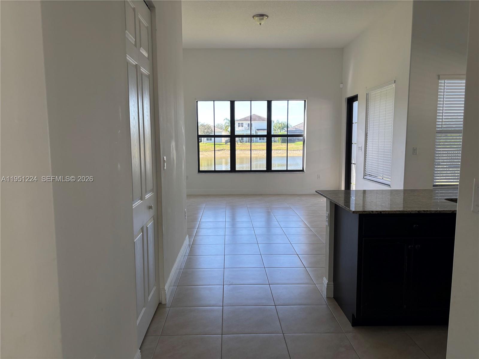 An interior view shows a tiled room with a large window overlooking a lake — 4783 Rosetta Terrace, Ave Maria FL 34142, AVE MARIA, FL