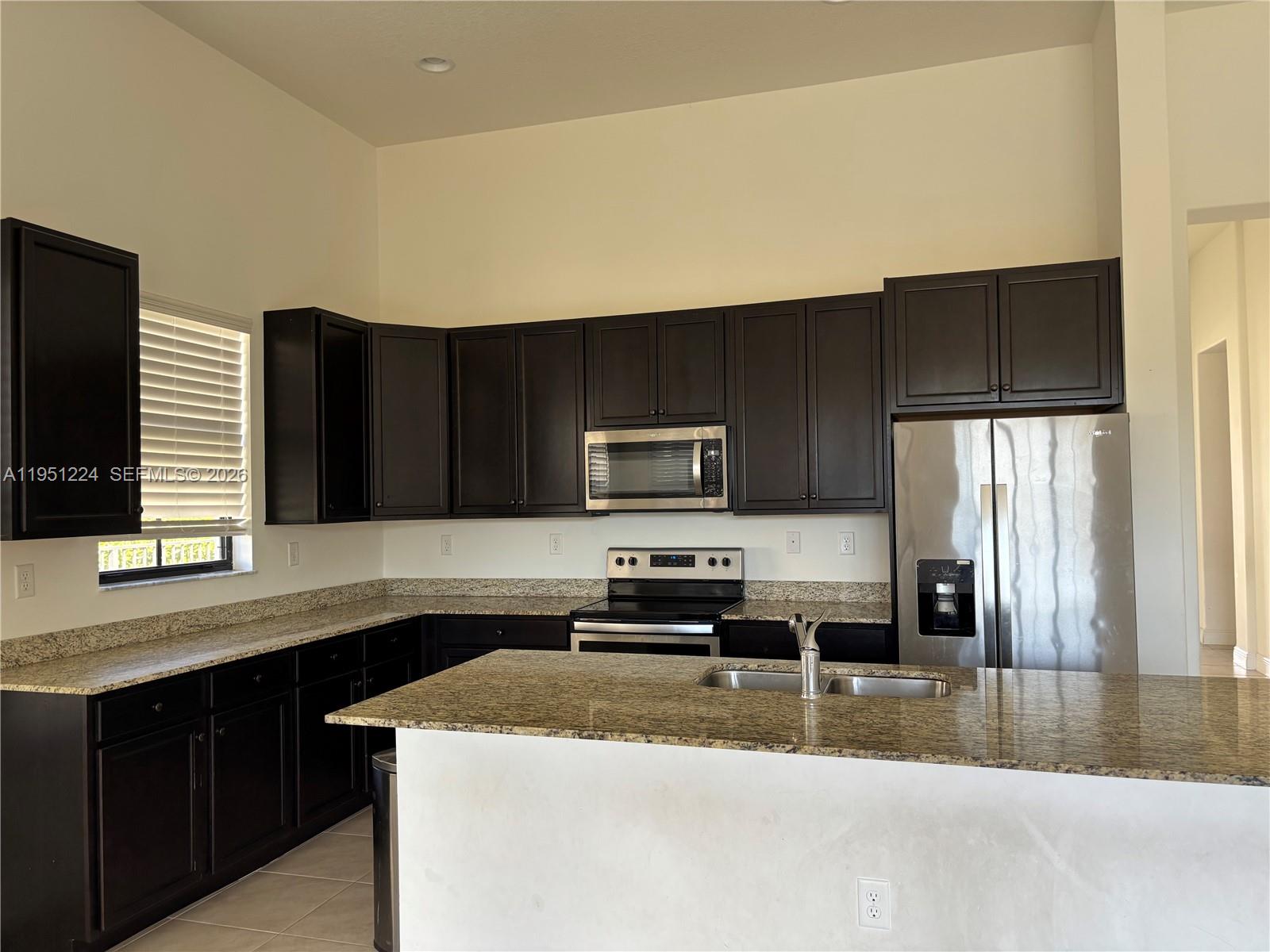 A kitchen features dark wood cabinets, granite countertops, and stainless steel appliances — 4783 Rosetta Terrace, Ave Maria FL 34142, AVE MARIA, FL