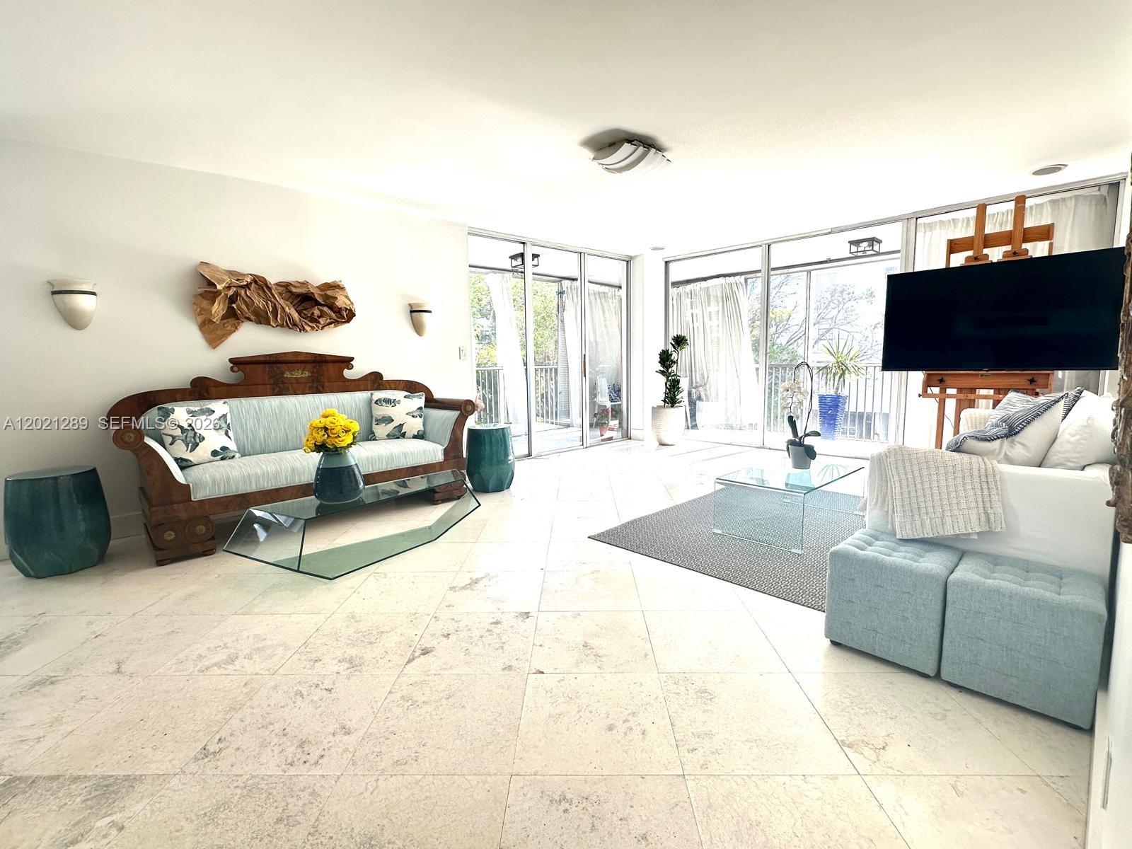 A bright living room features light tile floors, two seating areas, and large glass sliding doors — 150 Ocean Lane Dr # 2A, Key Biscayne FL 33149, KEY BISCAYNE, FL