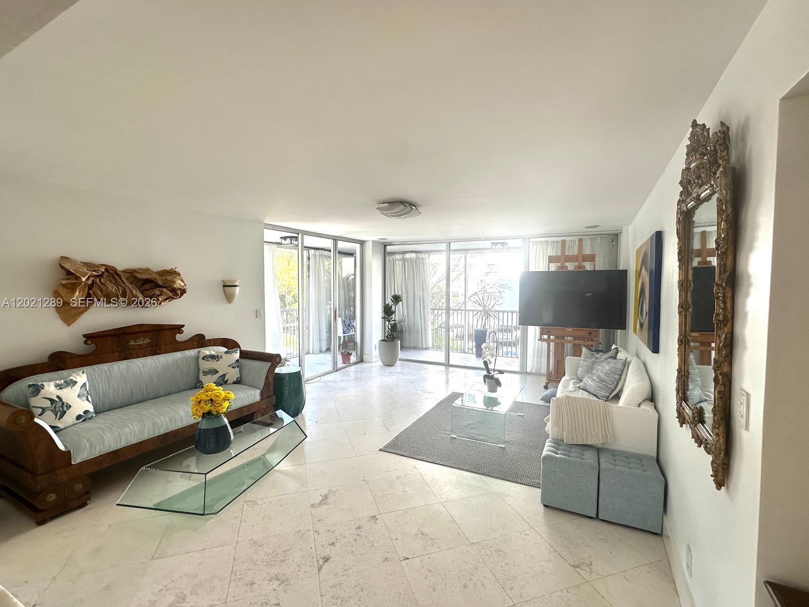 A living room features marble floors, two sofas, a glass coffee table, and large sliding doors — 150 Ocean Lane Dr # 2A, Key Biscayne FL 33149, KEY BISCAYNE, FL