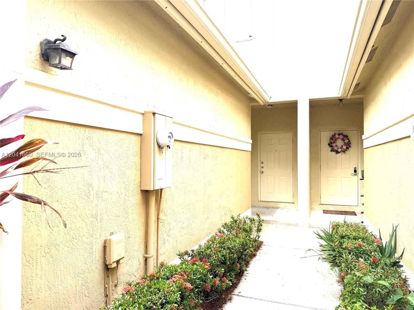 A walkway leads to two exterior doors flanked by bushes against a yellow stucco wall — 2560 Cordoba Bnd # 2560, Weston FL 33327, WESTON, FL