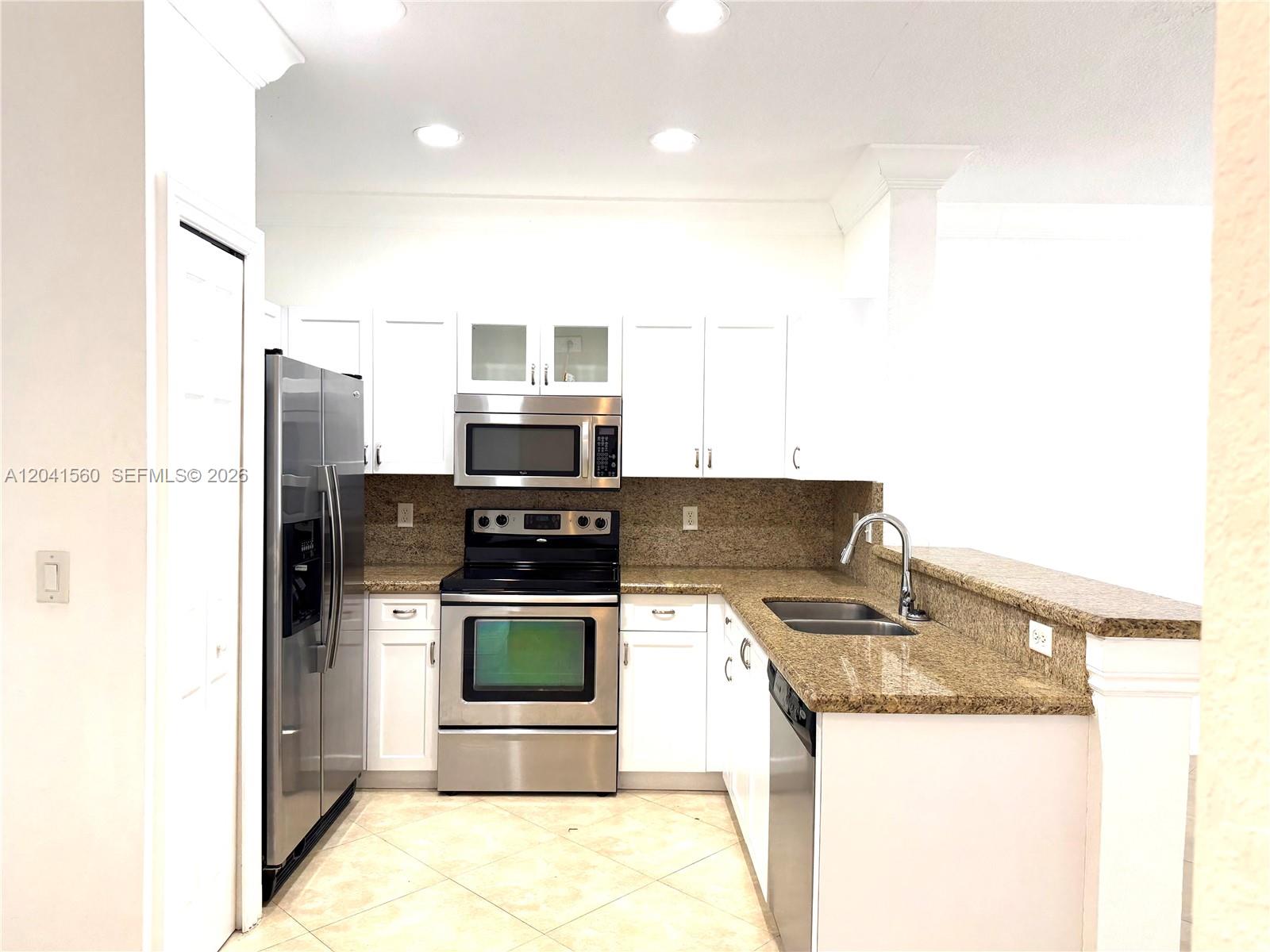A kitchen features white cabinets, stainless steel appliances, and speckled granite countertops — 2560 Cordoba Bnd # 2560, Weston FL 33327, WESTON, FL