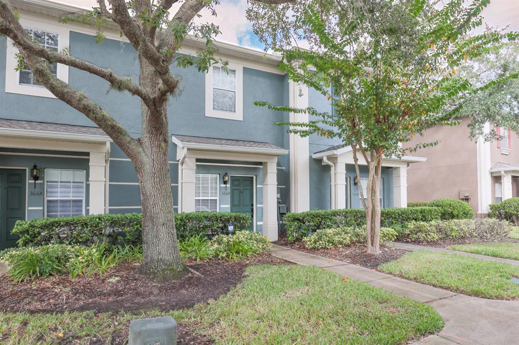 A row of blue two-story townhouses features white trim, front porches, and mature trees — 3664 WILSHIRE WAY ROAD UNIT 261, ORLANDO, FL