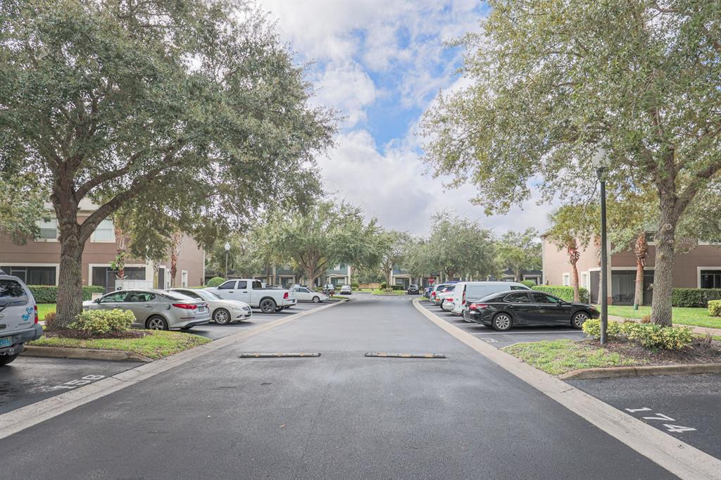 An outdoor view of a residential parking lot lined with trees and parked cars — 3664 WILSHIRE WAY ROAD UNIT 261, ORLANDO, FL