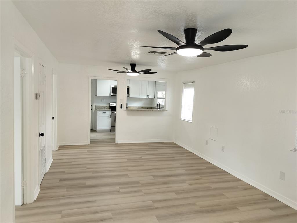 A living room with light wood-look flooring, white walls, and two ceiling fans — 2135 ELIZABETH STREET, LAKELAND, FL