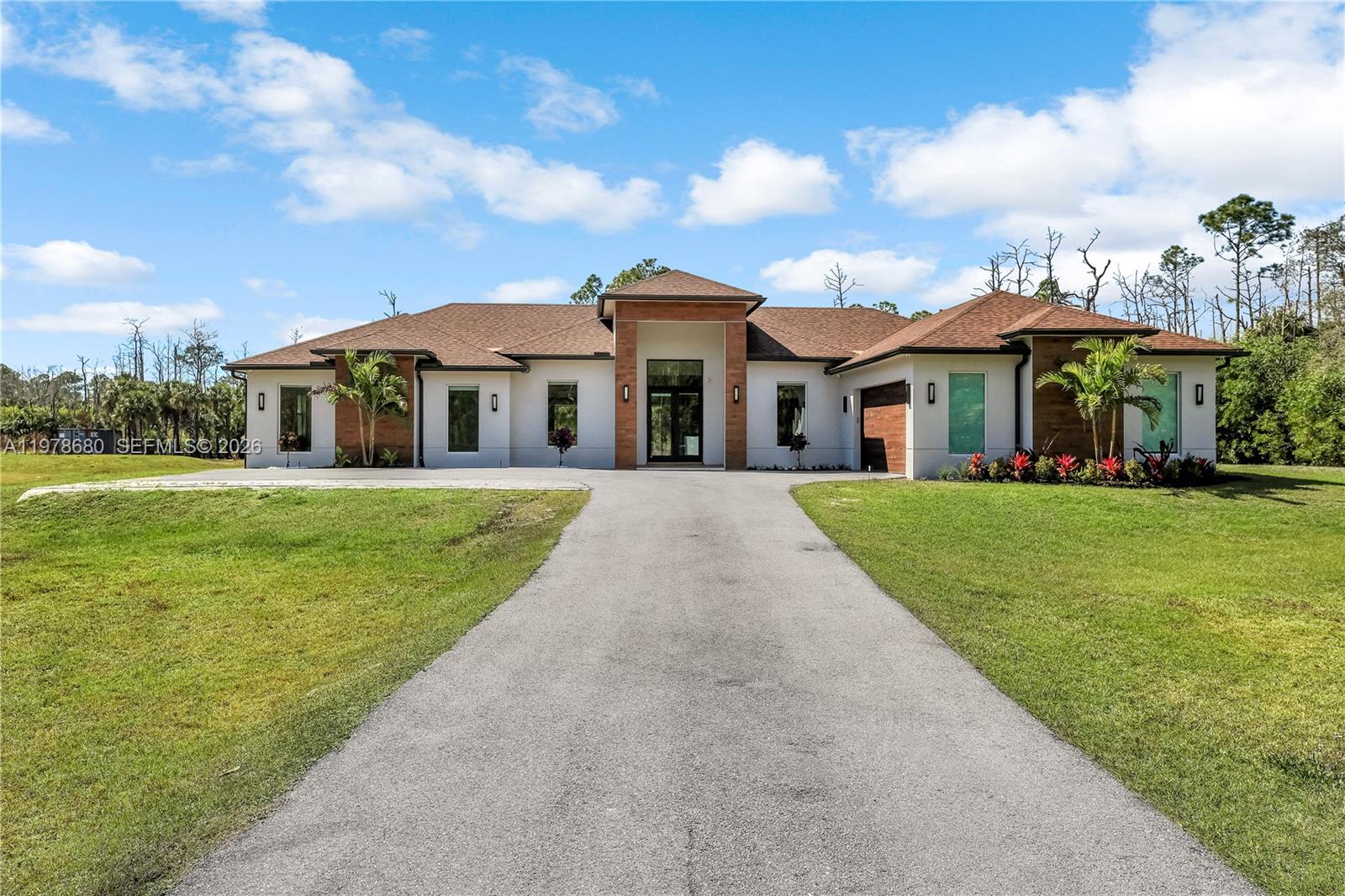 A modern single-story house with a brown roof, white walls, and a long asphalt driveway — 1899 Wilson Blvd N, Naples FL 34120, NAPLES, FL