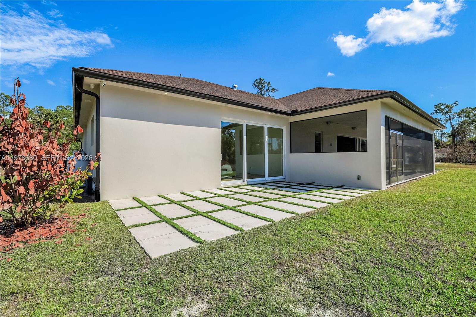 The exterior view shows a house with a paved patio and a screened-in porch — 1899 Wilson Blvd N, Naples FL 34120, NAPLES, FL