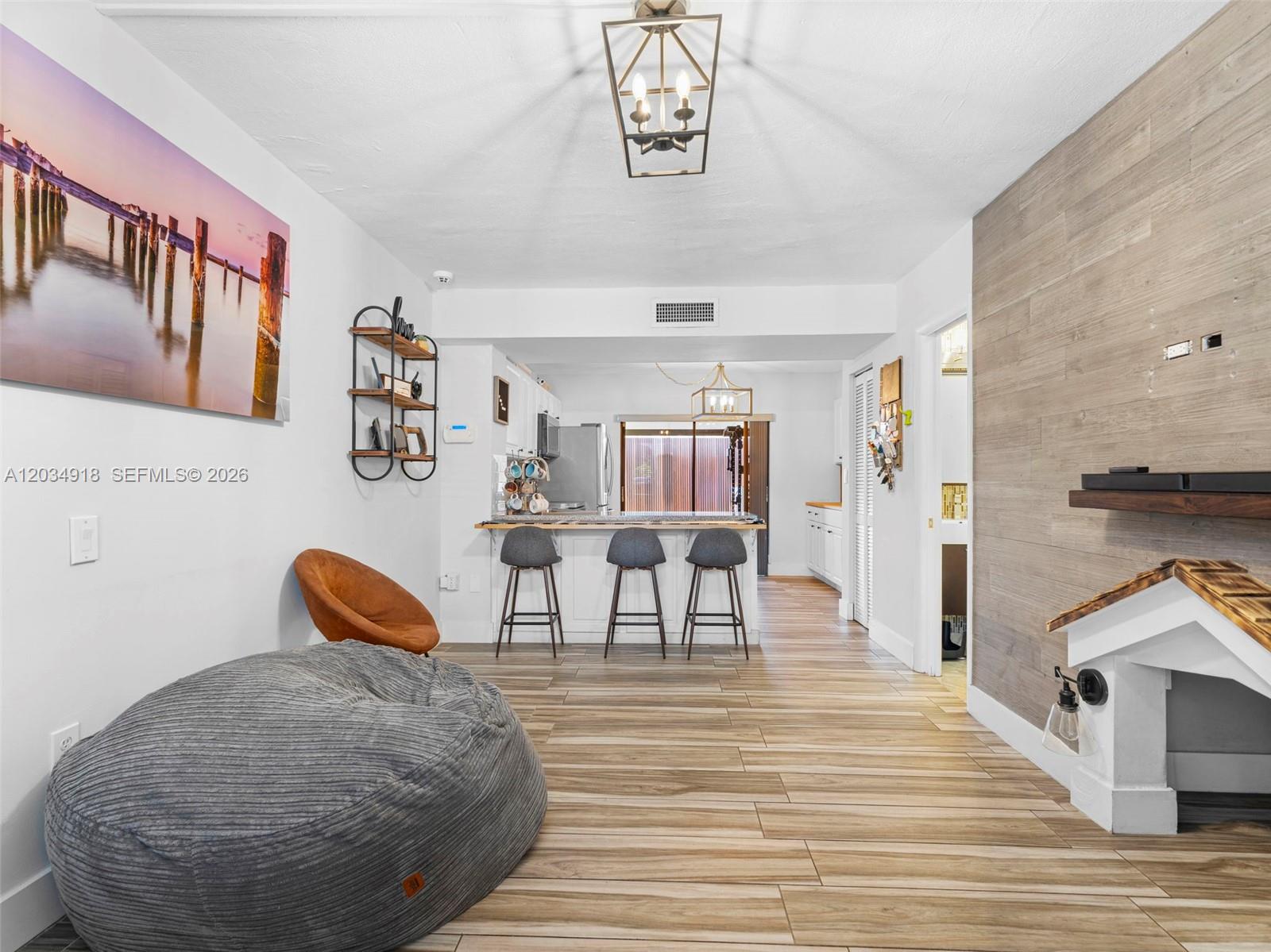 A living room with a beanbag chair, wood-look tile floors, and a kitchen breakfast bar — 1805 SW 107th Ave # 2601, Miami FL 33165, MIAMI, FL
