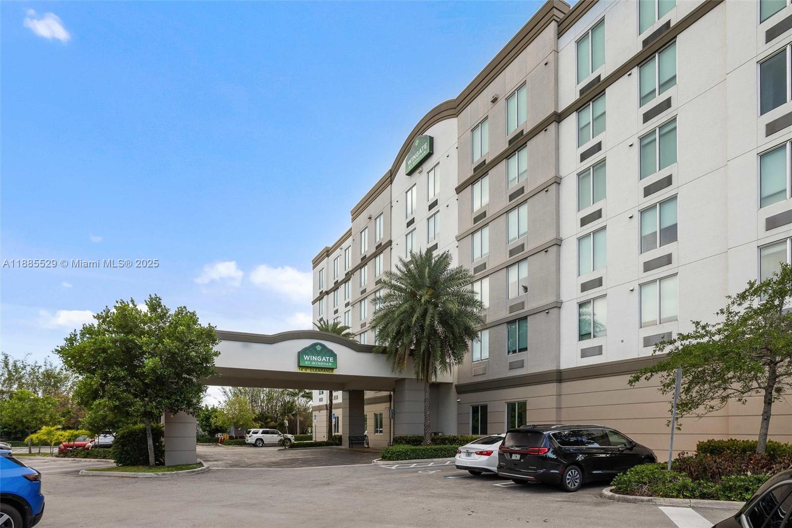 A multi-story hotel exterior features a covered entrance, a palm tree, and a parking lot — 3755 NW 78th Ave, Doral FL 33166, DORAL, FL