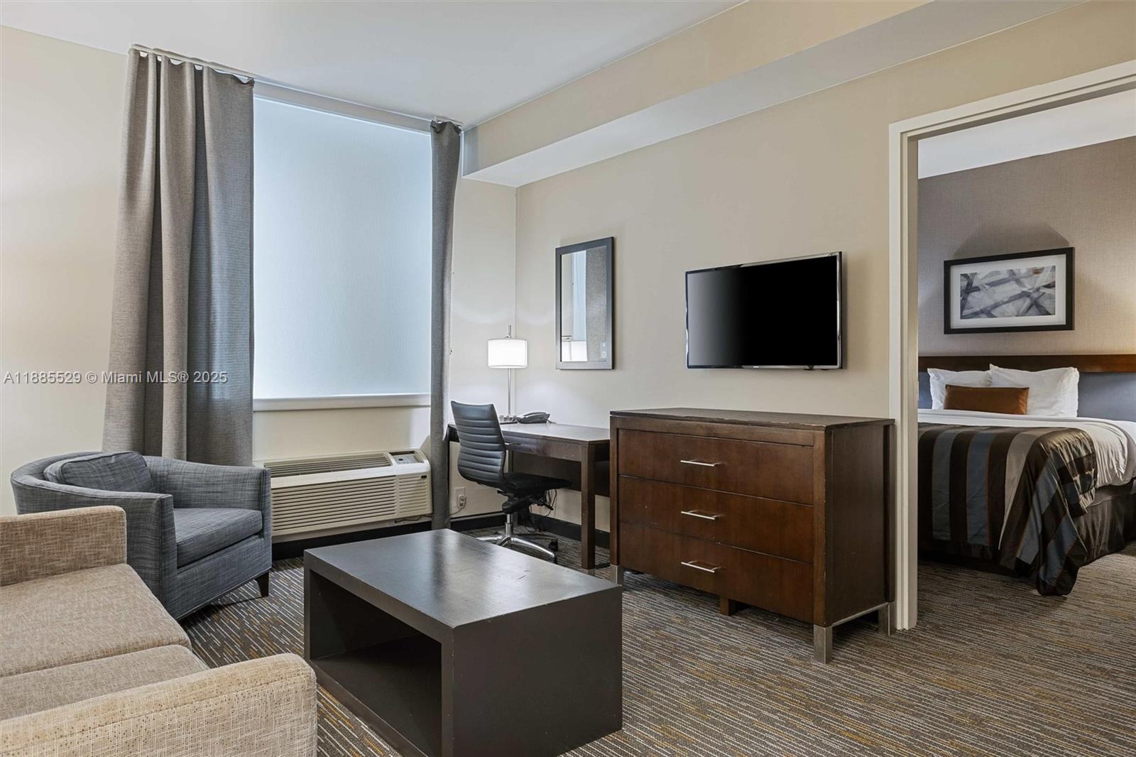 A hotel suite features a living area with a desk, dresser, and an adjoining bedroom — 3755 NW 78th Ave, Doral FL 33166, DORAL, FL
