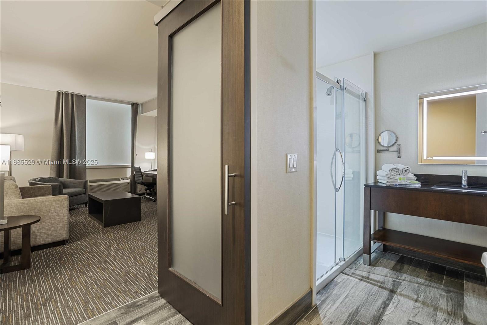 A hotel room features a bathroom with a glass shower and a vanity area — 3755 NW 78th Ave, Doral FL 33166, DORAL, FL