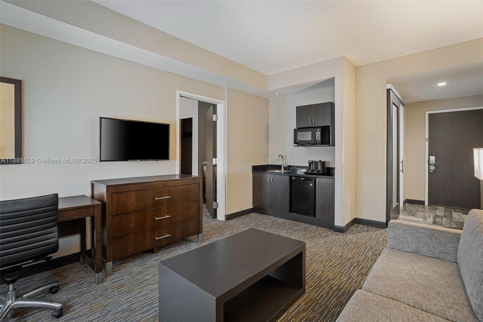 A hotel room features a kitchenette, a desk, a dresser, and a seating area — 3755 NW 78th Ave, Doral FL 33166, DORAL, FL