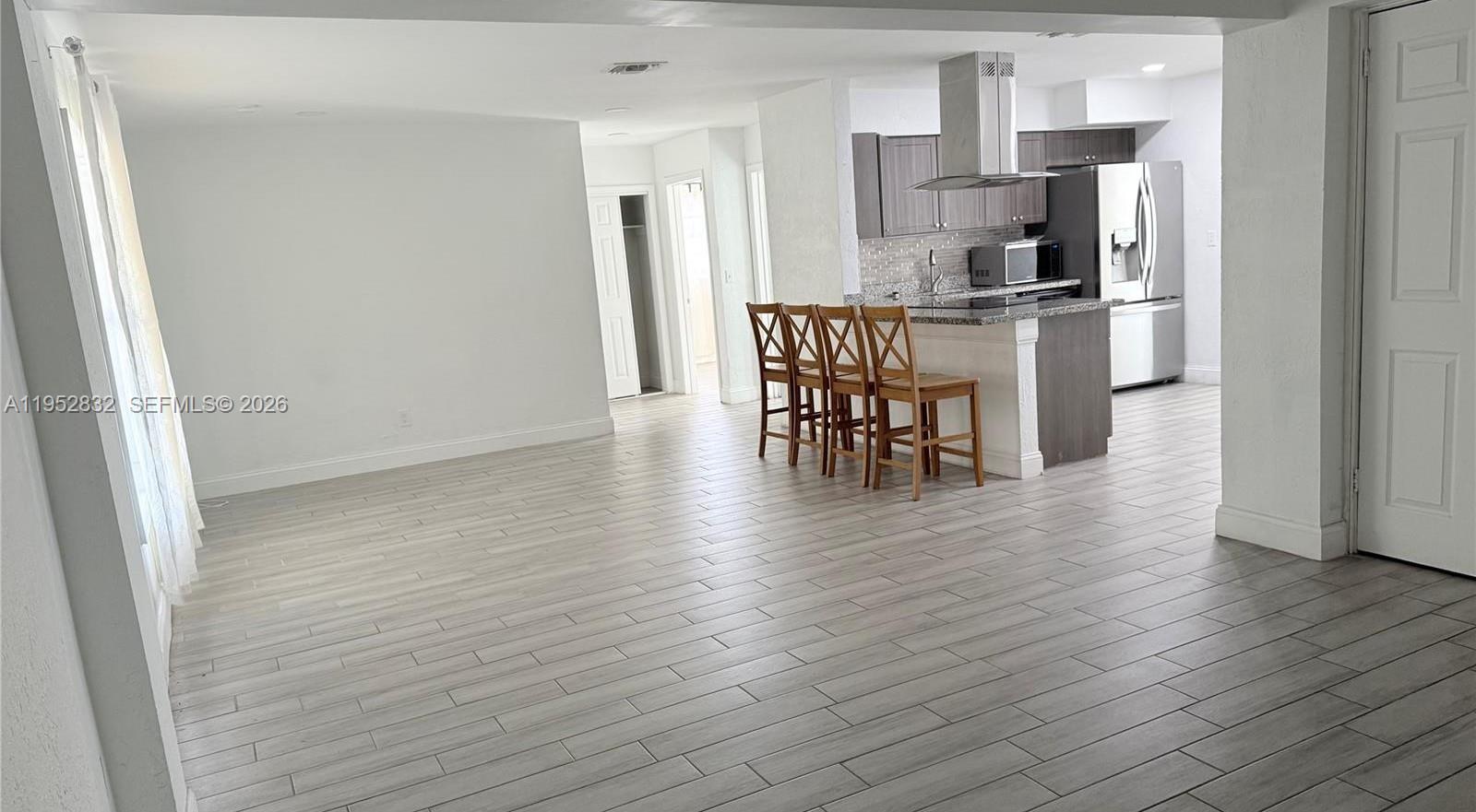 An open-concept living area features light wood-look tile flooring and a kitchen with bar seating — 4741 SW 25th Ter, Dania Beach FL 33312, DANIA BEACH, FL