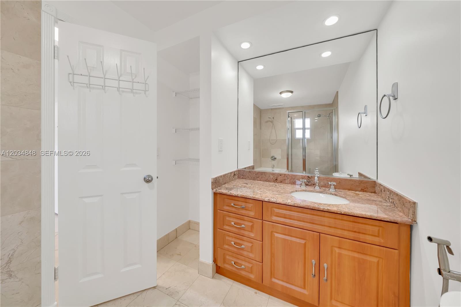 A bathroom features a wooden vanity with a granite countertop, a large mirror, and shelving — 7600 SW 19th Ter # C, Miami FL 33155, MIAMI, FL