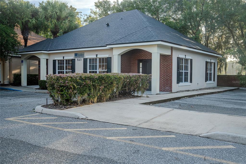 A single-story commercial building with a brick facade, arched entryway, and an asphalt parking lot — 523 WEKIVA COMMONS CIRCLE UNIT 4, APOPKA, FL