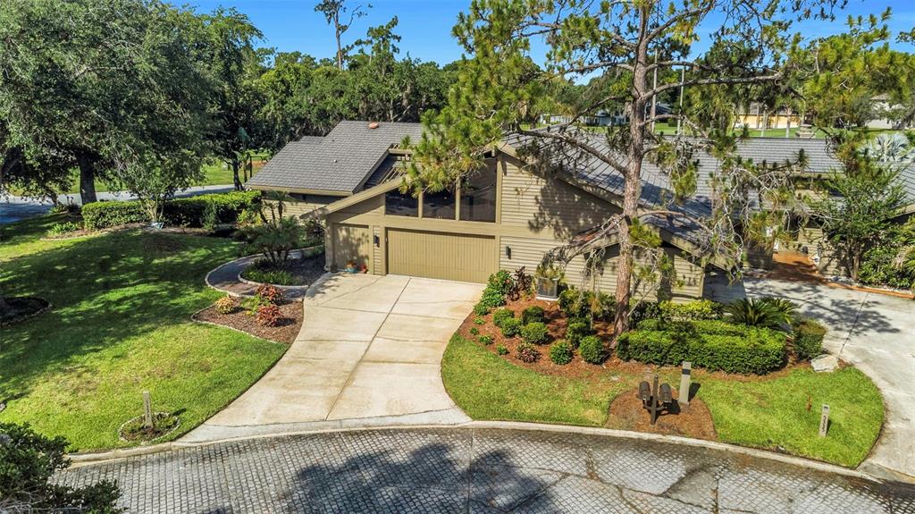 An elevated view of a tan house with a large garage and a concrete driveway — 5331 SAND CRANE COURT, WESLEY CHAPEL, FL