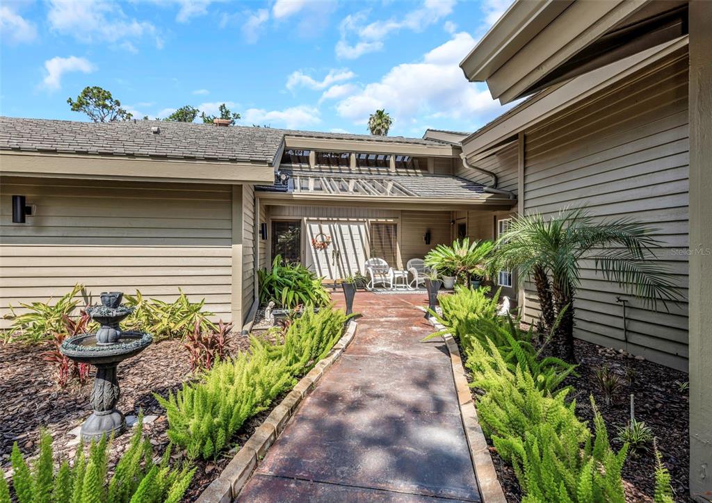 A paved walkway leads to the front entrance of a house with tan horizontal siding — 5331 SAND CRANE COURT, WESLEY CHAPEL, FL