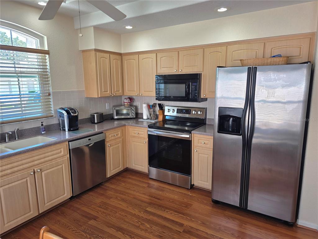 A kitchen features light wood cabinets, stainless steel appliances, and wood-look flooring — 225 ROYAL PALM WAY, SPRING HILL, FL