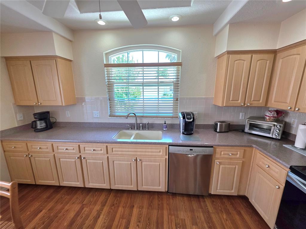 A kitchen features light wood cabinets, a stainless steel dishwasher, and a window above the sink — 225 ROYAL PALM WAY, SPRING HILL, FL