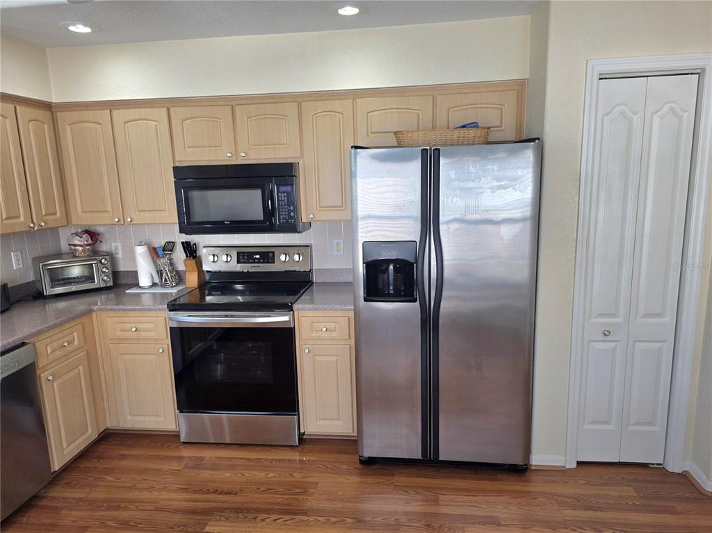A kitchen features light wood cabinets, stainless steel appliances, and wood-look flooring — 225 ROYAL PALM WAY, SPRING HILL, FL