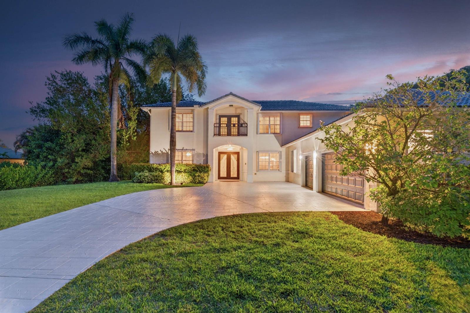 A two-story house with a paved driveway, palm trees, and a multi-car garage at dusk — 8346 Sawpine Road, Delray Beach FL 33446, DELRAY BEACH, FL