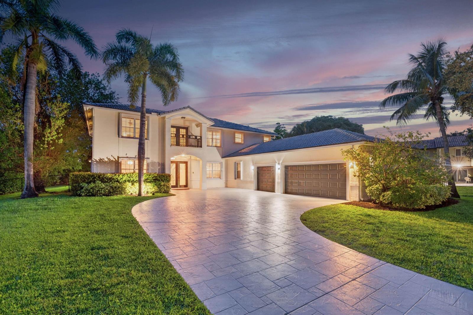 A two-story house with a paved driveway, palm trees, and a three-car garage at dusk — 8346 Sawpine Road, Delray Beach FL 33446, DELRAY BEACH, FL
