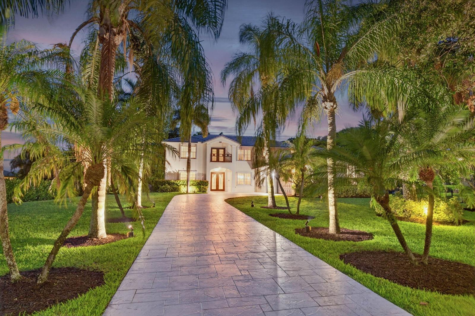 A paved driveway leads to a two-story house surrounded by palm trees at dusk — 8346 Sawpine Road, Delray Beach FL 33446, DELRAY BEACH, FL