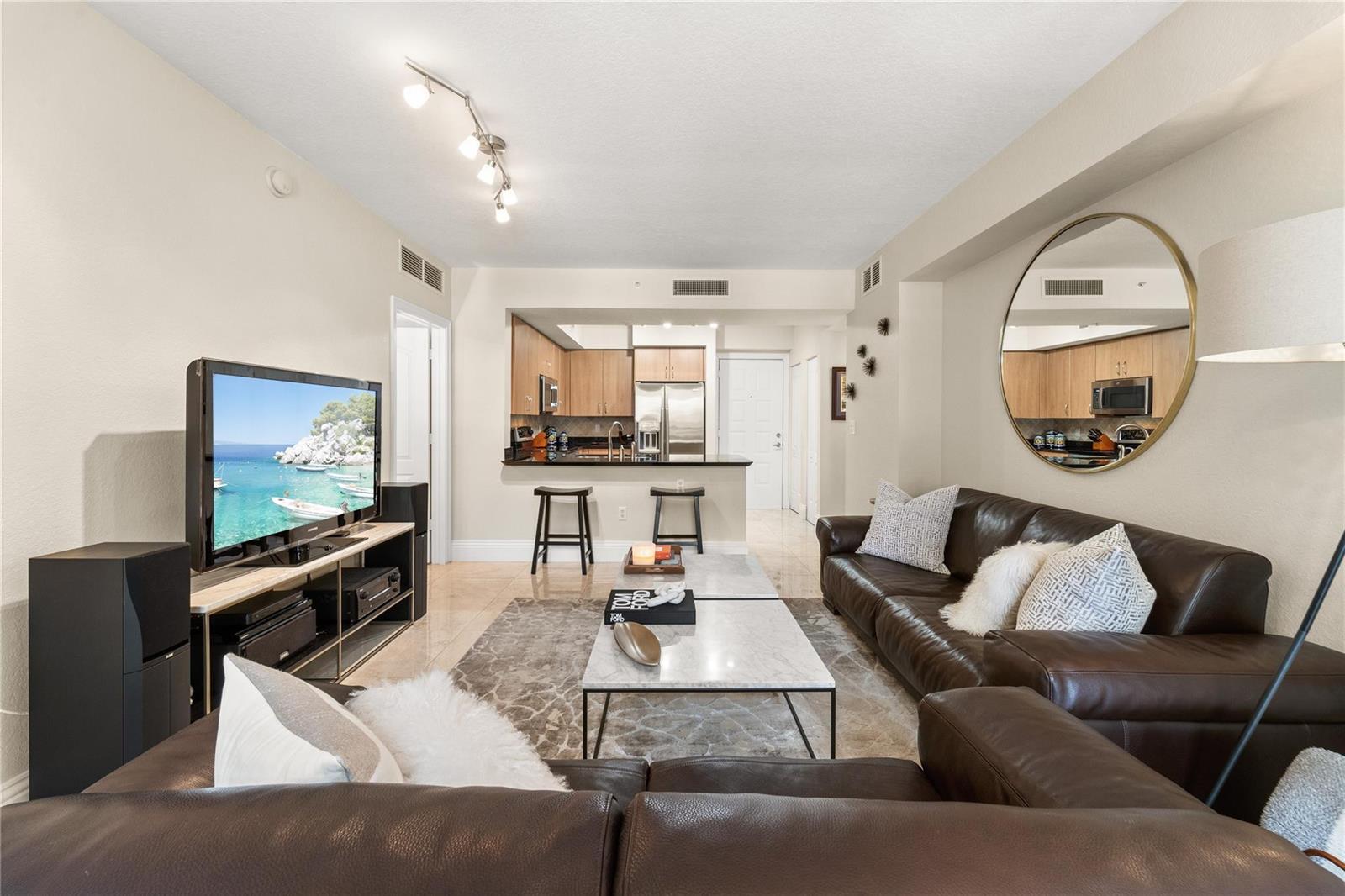 A living room with a brown leather sectional, marble coffee table, and open kitchen area — 1830 Radius Drive # 303, Hollywood FL 33020, HOLLYWOOD, FL