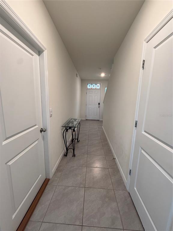 A narrow hallway features tile flooring, two white doors, and a small glass-topped console table — 3521 MAPLE GROVE WAY, PLANT CITY, FL